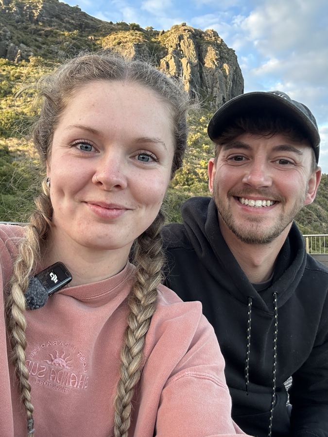 Ashleigh and Luke smiling in front of a rocky hill